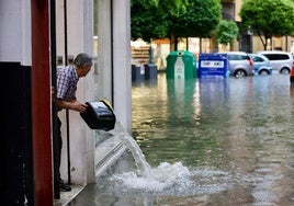 Un comerciante achica agua de su negocio en la calle Esgueva