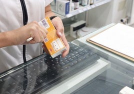 Una farmacéutica corta el código de barras de un medicamento.
