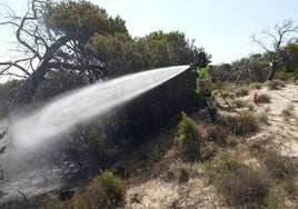 Un incendio trabajando este sábado en una zona afectada por el fuego.